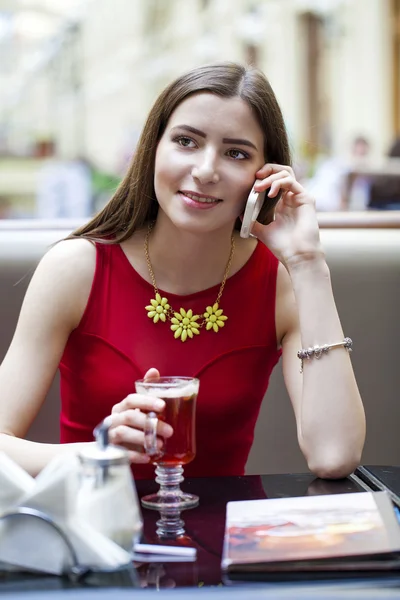 Menina morena bonita sentada em uma cafeteria — Fotografia de Stock