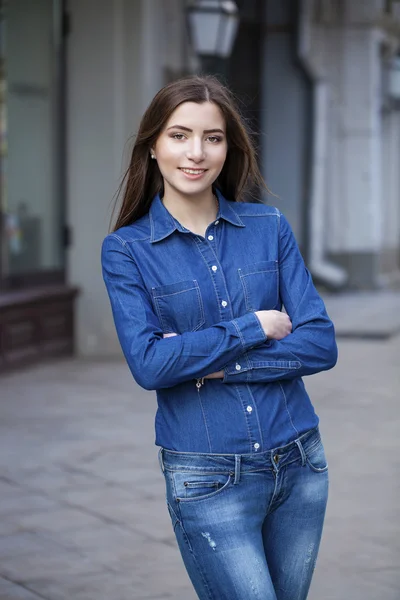 Portrait of a beautiful young woman in a blue jeans shirt on the — Stock Photo, Image