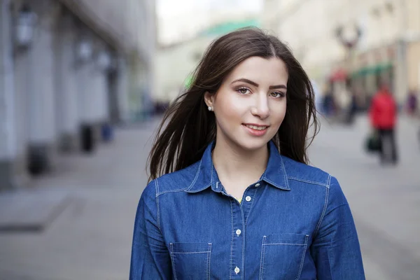 Portrait of a beautiful young woman in a blue jeans shirt on the — Stock Photo, Image