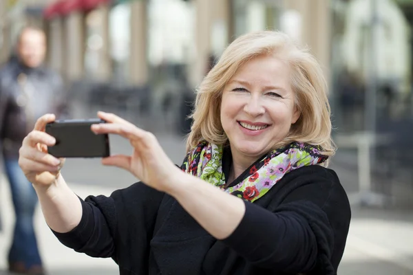 Glücklich reifen schönen blonden Frau auf einem Handy fotografiert — Stockfoto