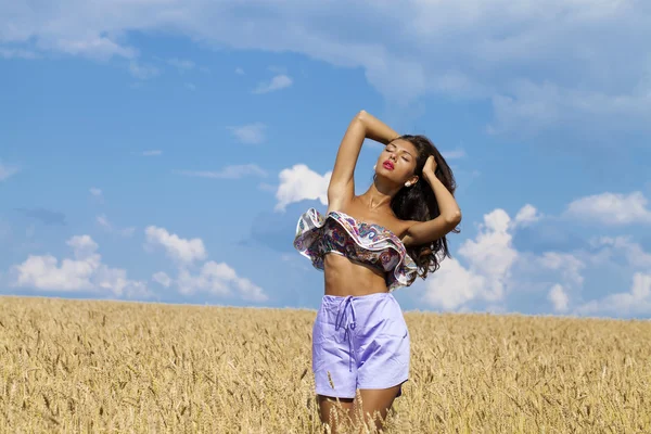 Sexy giovane donna in pantaloncini blu in un campo d'oro di grano — Foto Stock