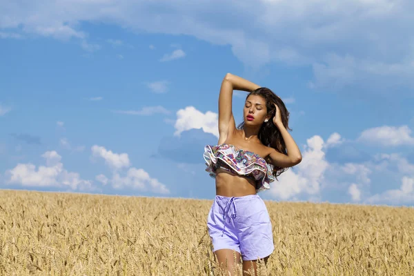Sexy giovane donna in pantaloncini blu in un campo d'oro di grano — Foto Stock