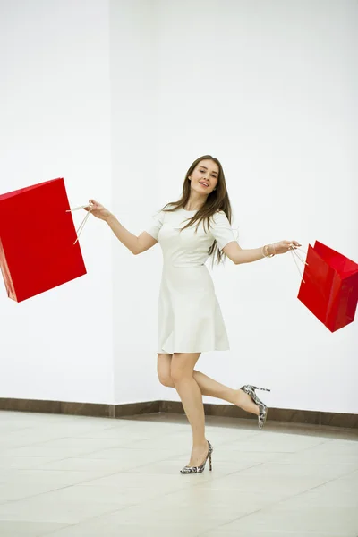 Щаслива жінка тримає два червоних сумки, що йдуть в магазині — стокове фото