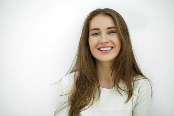 Hermosa joven feliz mujer posando contra una pared blanca —  Fotos de Stock