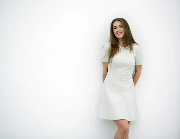 Hermosa mujer joven en un vestido gris claro posando contra un whi — Foto de Stock