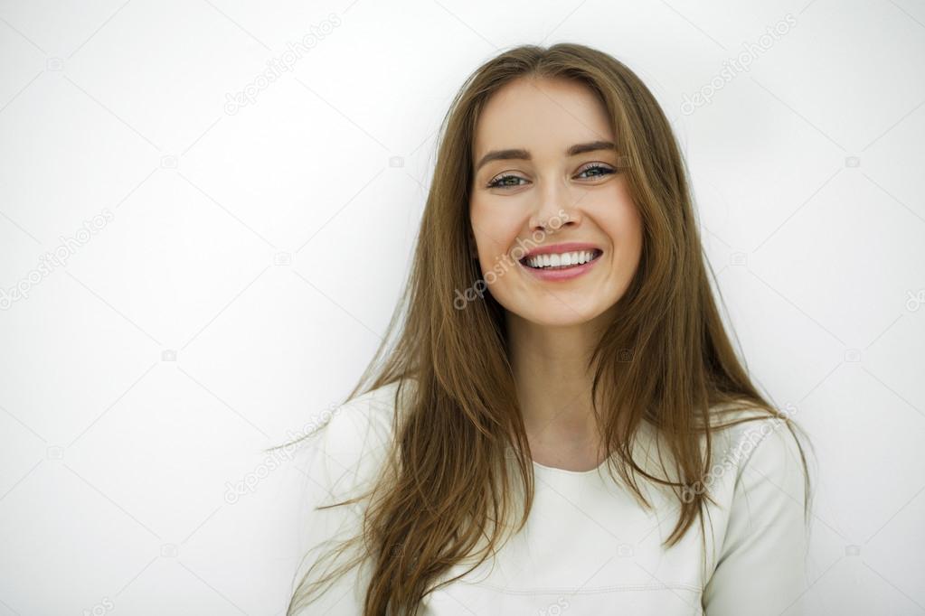 Beautiful young happy woman posing against a white wall