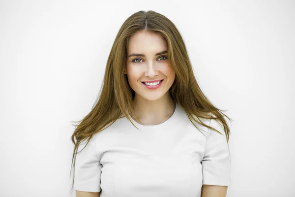 Hermosa joven feliz mujer posando contra una pared blanca —  Fotos de Stock