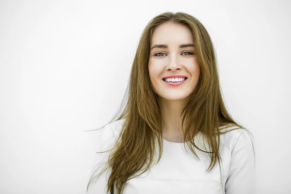 Hermosa joven feliz mujer posando contra una pared blanca — Foto de Stock