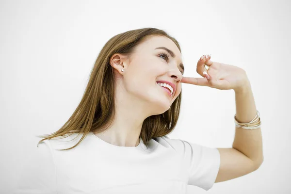 Schöne junge glückliche Frau posiert vor einer weißen Wand — Stockfoto