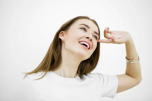 Mulher feliz bonita jovem posando contra uma parede branca — Fotografia de Stock