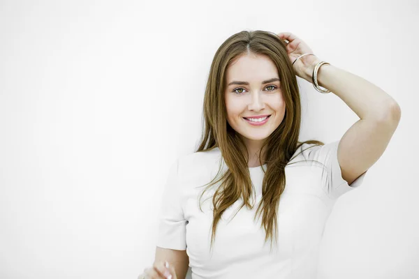 Mooie jonge gelukkig vrouw poseren tegen een witte muur — Stockfoto