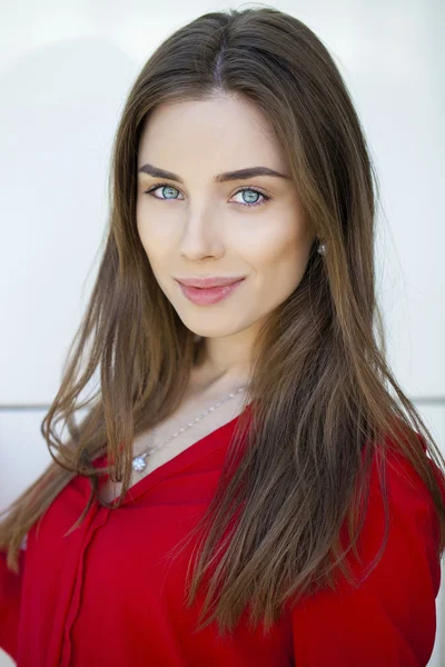 Güzel bir genç kız beyaz wal üzerinde kırmızı gömlekli portresi — Stok fotoğraf