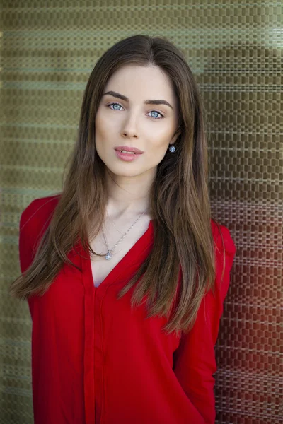 Portret van een mooi jong meisje in rood shirt op de muur — Stockfoto