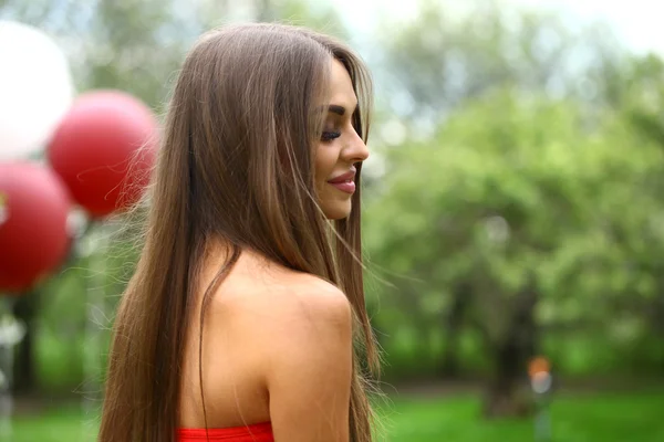 Happy young woman in red dress against the background spring flo — Stock Photo, Image