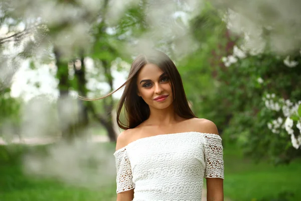 Happy young woman in white dress against the background spring f — Stock Photo, Image