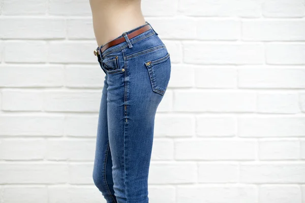 Krásná žena tělo v modré džíny na bílých cihel na zeď poz — Stock fotografie