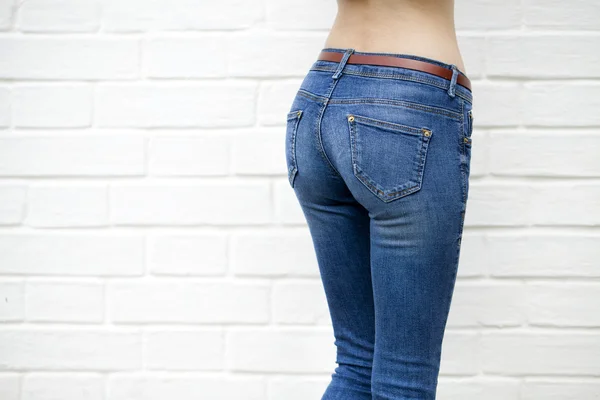 Güzel bir kadın vücut denim Jeans üzerinde beyaz tuğla duvar backgrou — Stok fotoğraf