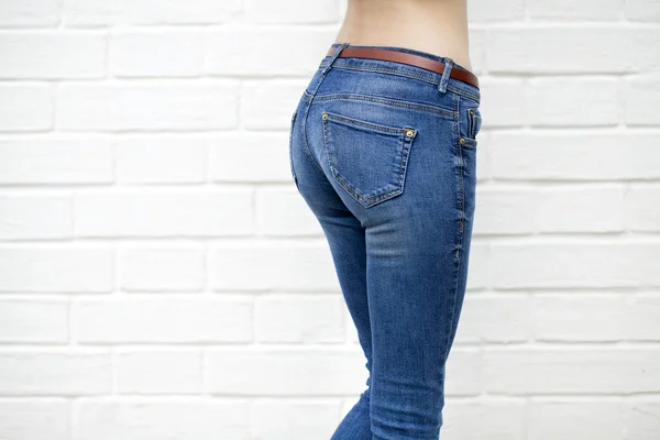 Beautiful woman body in denim jeans on white brick wall backgrou — Stock Photo, Image