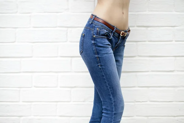 Beautiful woman body in denim jeans on white brick wall backgrou — Stock Photo, Image