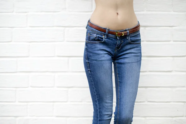 Corpo de mulher bonita em jeans jeans jeans na parede de tijolo branco backgrou — Fotografia de Stock