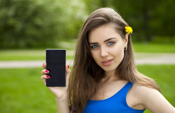 Young beautiful brunette woman shows a new smart phone — Stock Photo, Image