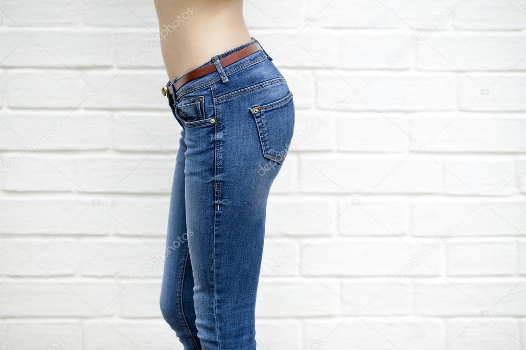 Beautiful woman body in denim jeans on white brick wall backgrou