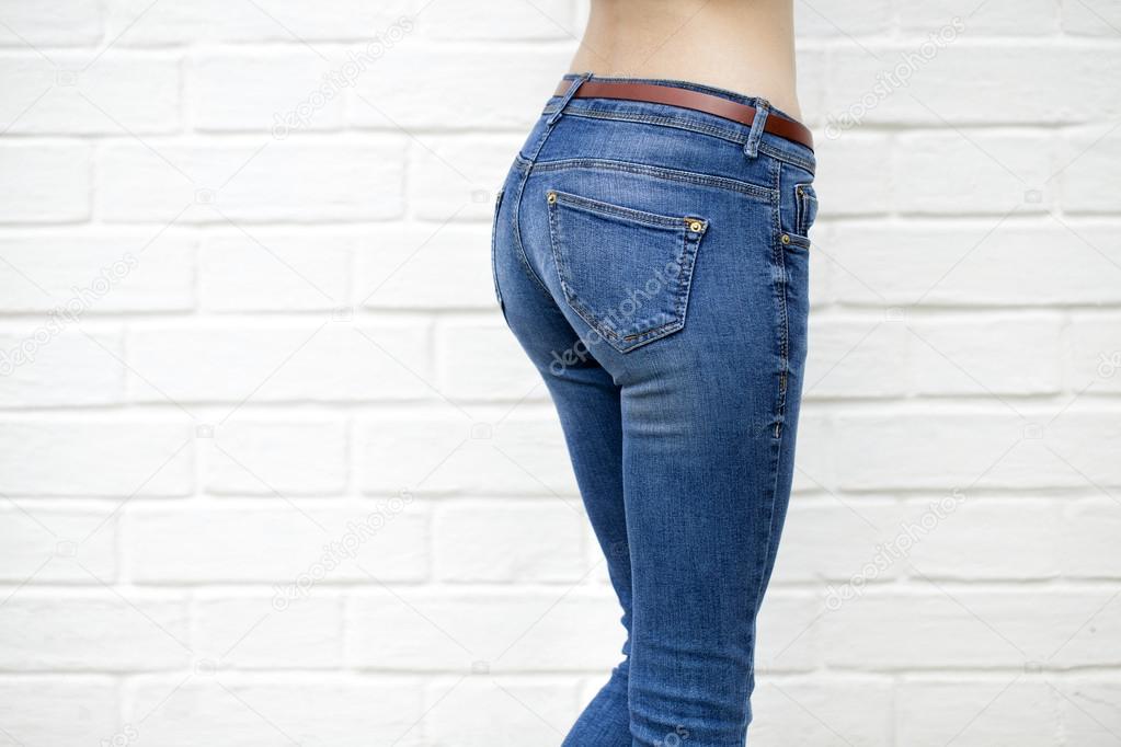 Beautiful woman body in denim jeans on white brick wall backgrou