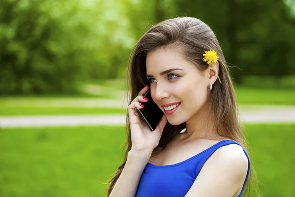 Красивая брюнетка звонит по телефону в летнем парке — стоковое фото