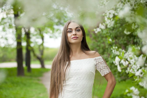 Happy young woman in white dress against the background spring f — Stock Photo, Image