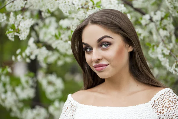 Happy young woman in white dress against the background spring f — Stock Photo, Image