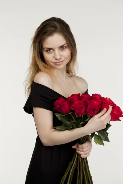 Retrato de uma jovem menina bonita com um buquê de rosas vermelhas — Fotografia de Stock