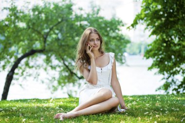 Mutlu güzel sarışın kız bir yaz parkta telefonla arama