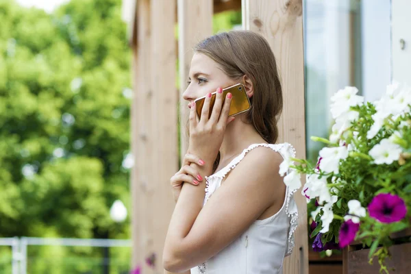 Menina loira bonita feliz chamando por telefone em uma rua de verão — Fotografia de Stock