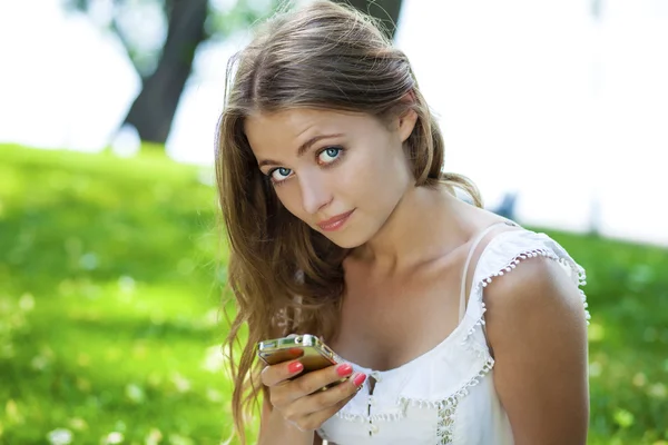 Gelukkig mooie blonde meisje bellen via de telefoon in een zomer-straat — Stockfoto