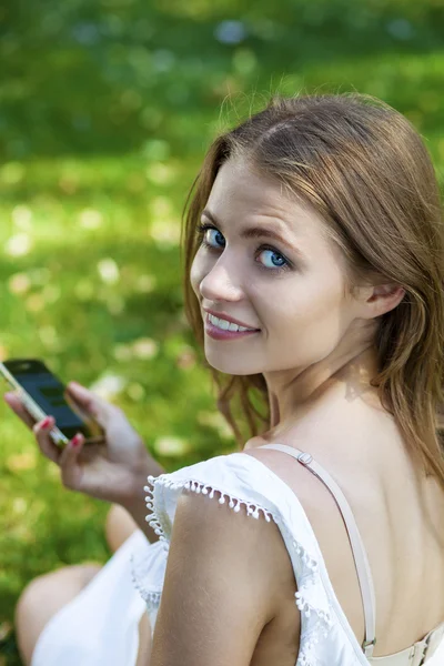 Happy beautiful blonde girl calling by phone in a summer street — Stock Photo, Image