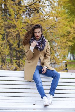 S bir bankta oturmuş bej bir palto Genç güzel kız