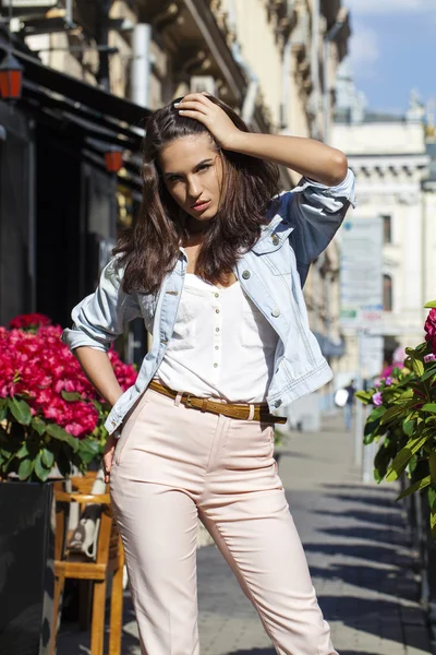 Ung brunett kvinna i jeans jackor gå på gatan — Stockfoto