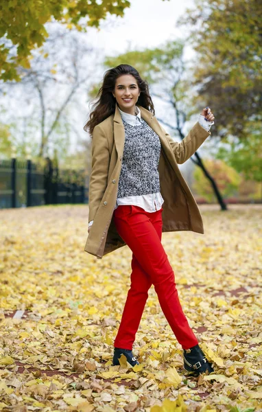 Young woman in fashion coat walking in autumn park — Stock Photo, Image