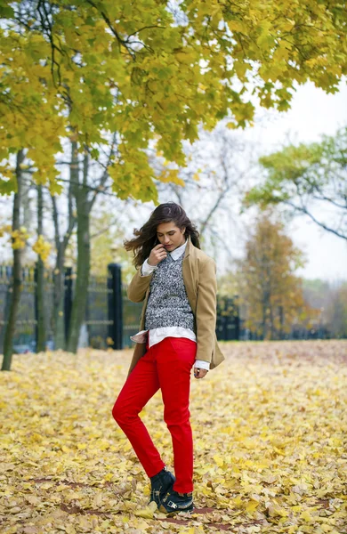 Young woman in fashion coat walking in autumn park — Stock Photo, Image