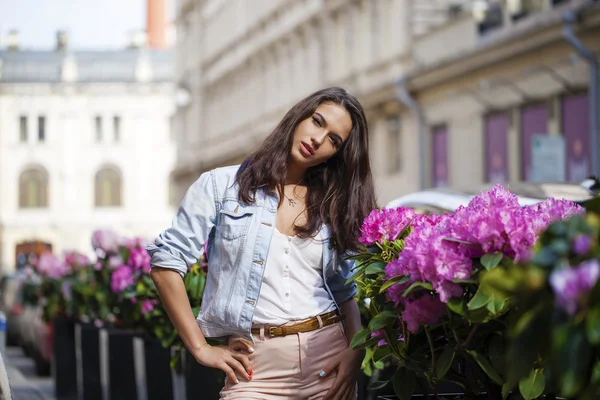 Ung brunett kvinna i jeans jackor gå på gatan — Stockfoto