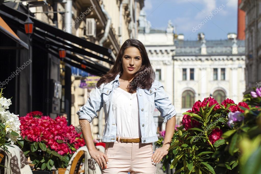 Young brunette woman in jeans jackets walking on the street
