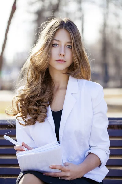 Retrato de una joven colegiala rubia sentada en el banco — Foto de Stock