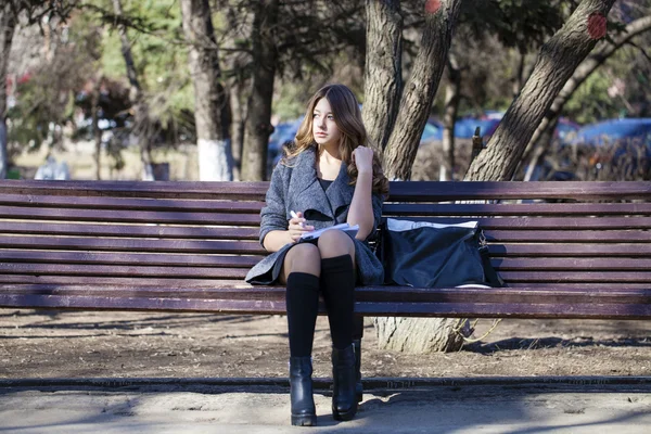 Retrato de una joven colegiala rubia sentada en el banco — Foto de Stock