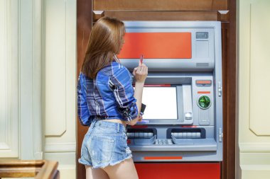 genç kadın bir otomatik vezne makinesi kullanarak kısa kot pantolon 