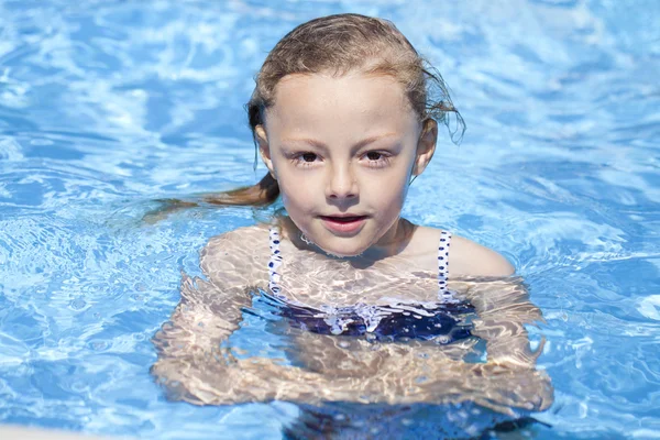 Child girl in blue bikini near swimming pool. Hot Summer