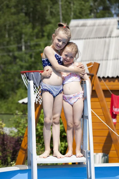 Две сестры в бикини рядом с бассейном. Горячее лето — стоковое фото