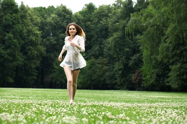 Fiatal gyönyörű lány a fehér ing van futás-ra a zöld — Stock Fotó