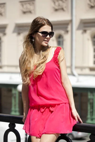 Young beautiful woman in red short dress posing outdoors in sunn — Zdjęcie stockowe