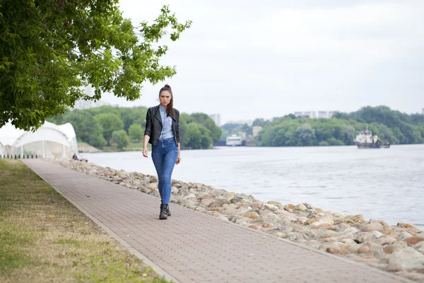 Młoda piękna dziewczyna w niebieskie dżinsy i niebieską bluzkę na backg — Zdjęcie stockowe