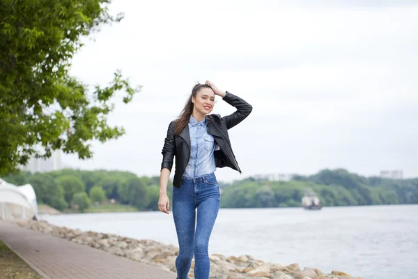 Joven hermosa chica en pantalones vaqueros azules y una camisa azul en la espalda —  Fotos de Stock